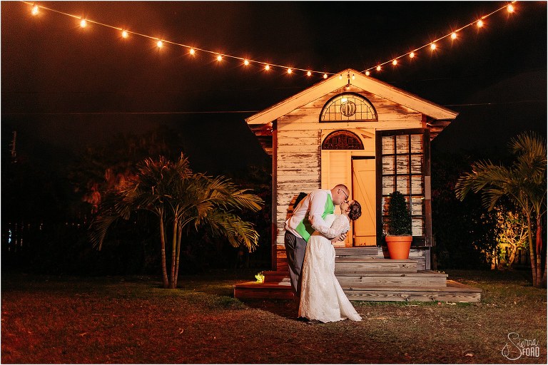 groom dips bride and kisses her under market lights at night at The Acre Orlando wedding