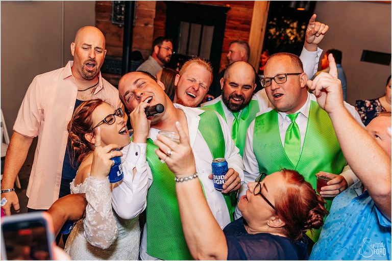 bride and guests belt out song into microphone at The Acre Orlando wedding reception