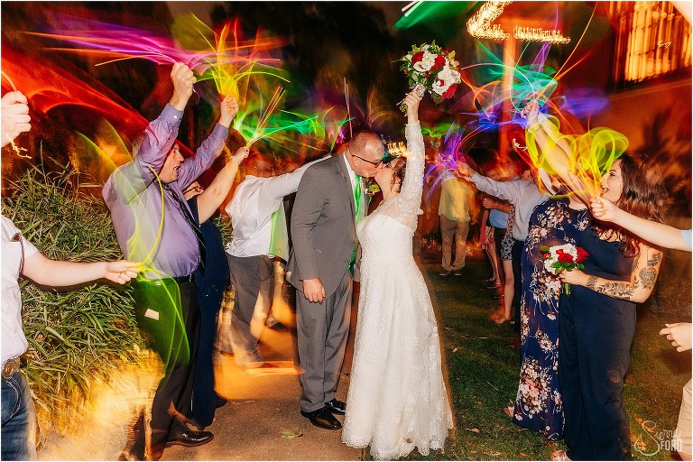 bride and groom share kiss as guests wave glow sticks around them at The Acre Orlando wedding