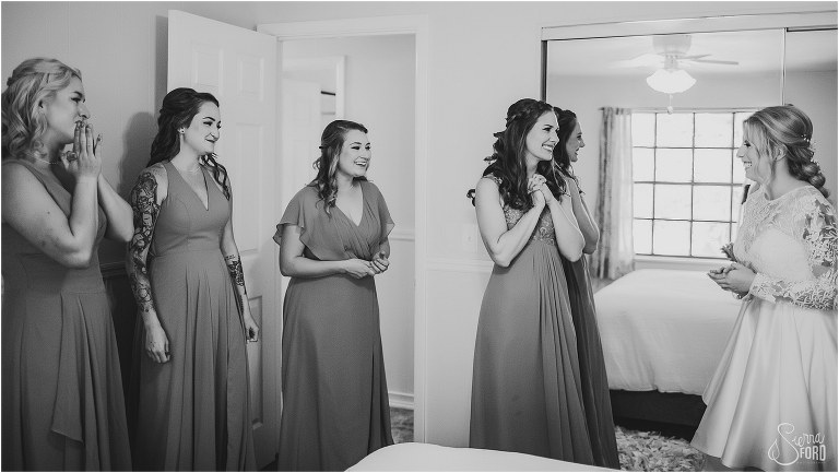 bridesmaids smile through tears as they see bride in dress for first time at Bridle Oaks wedding