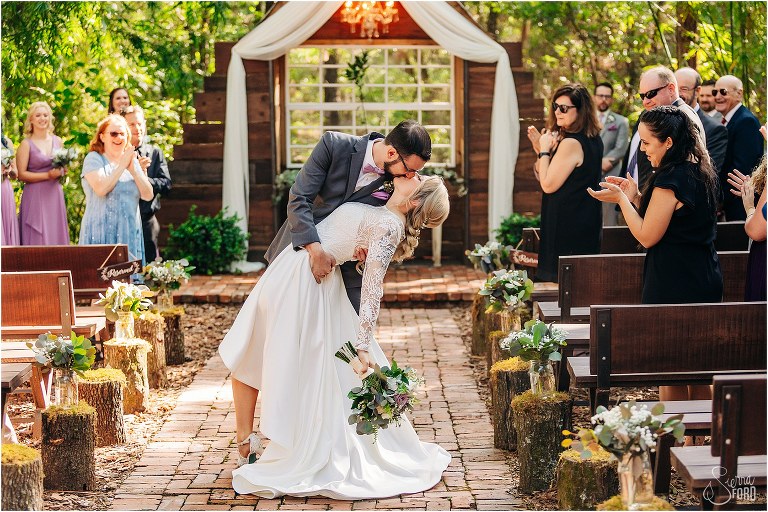 groom dips bride and kisses her in Bridle Oaks wedding photos