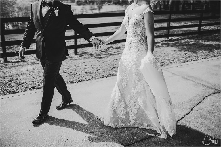 black and white photo of groom leading bride down path at rustic Apopka wedding