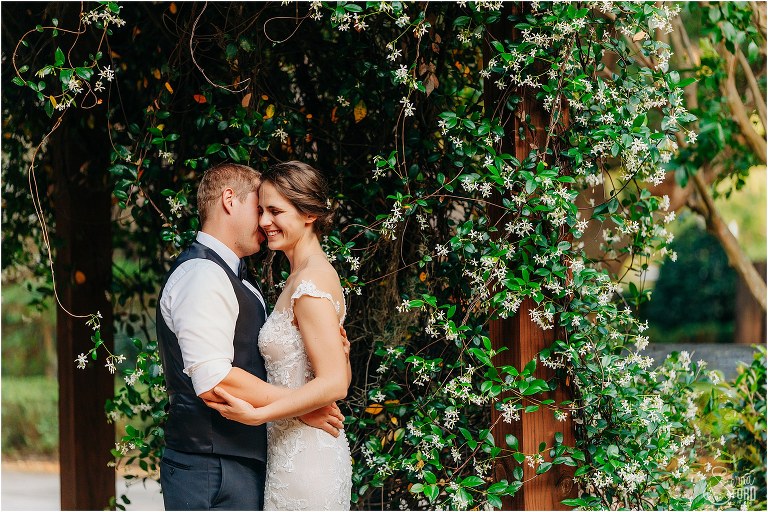 bride laughs as groom whispers in her ear near the ivy at rustic Apopka wedding