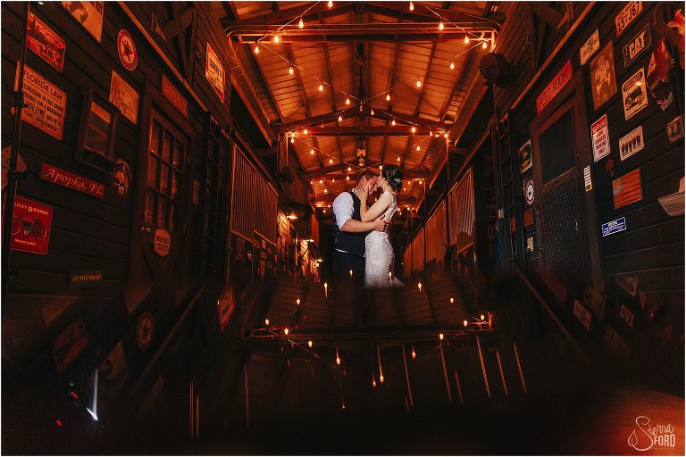 bride kisses groom's forehead in the garage lit with twinkle lights at rustic Apopka wedding