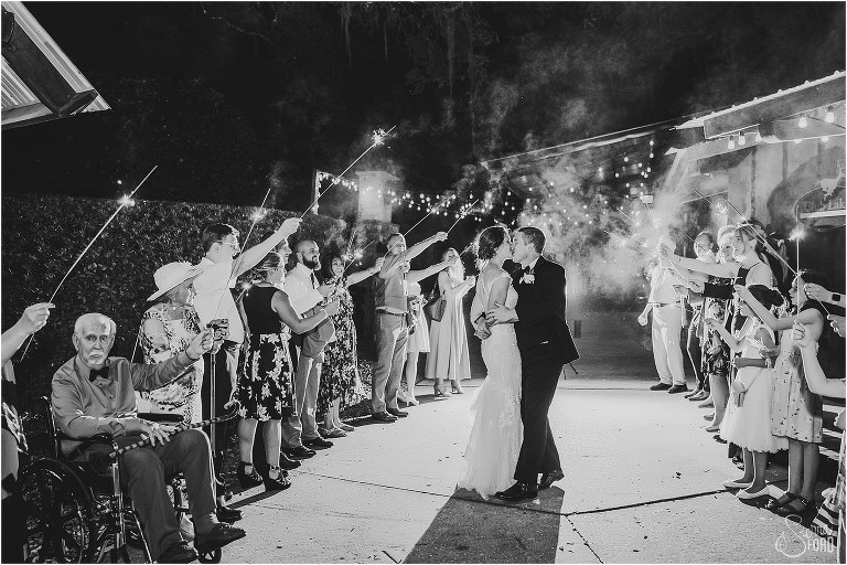 bride and groom kiss under sparklers held by guests while exiting rustic Apopka wedding
