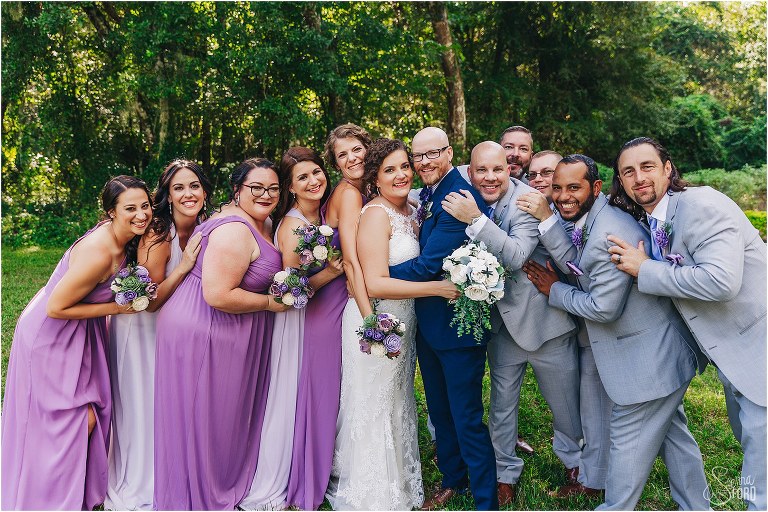 wedding party laughs as they swarm bride & groom for group hug after October Oaks wedding ceremony